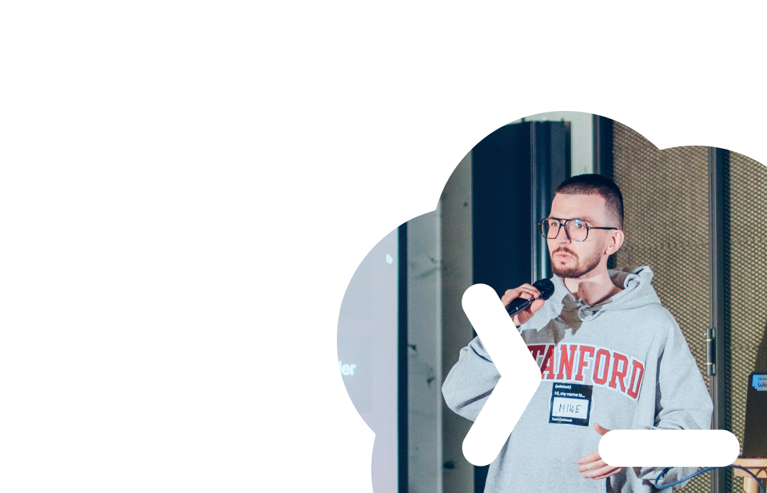 Man wearing glasses and a Stanford sweatshirt speaking into a microphone during a presentation.