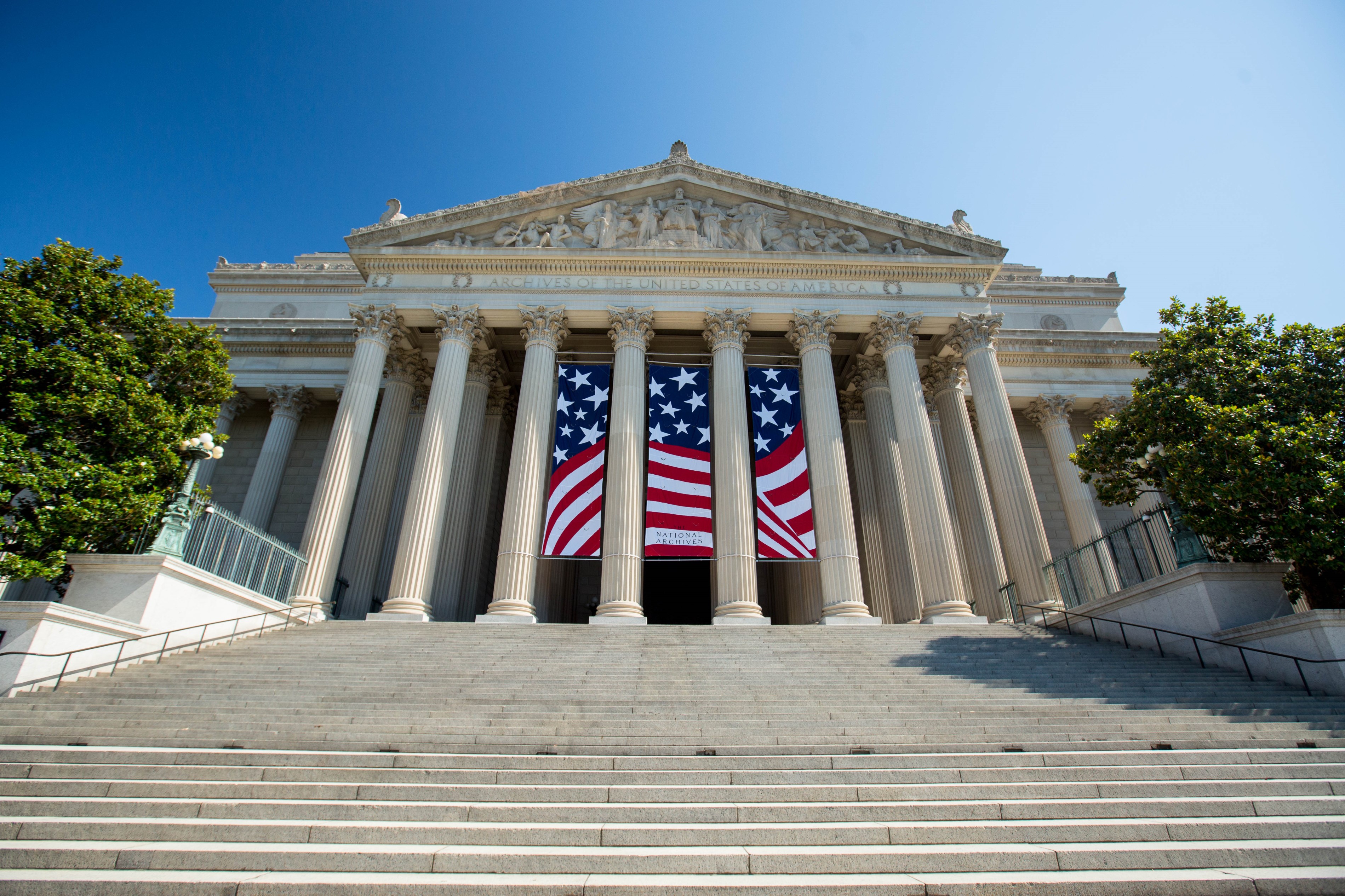 A large building with three large American flag banners hung between pillars
