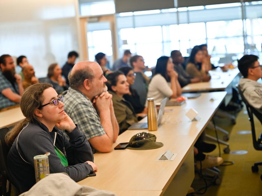 A group of current scientists listen to a talk during a symposium.