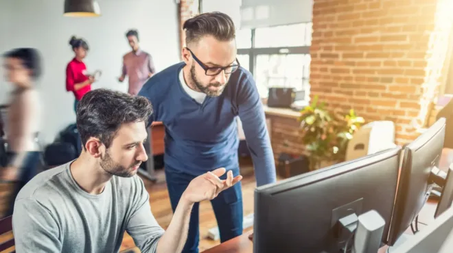 Image of two men working at a computer.