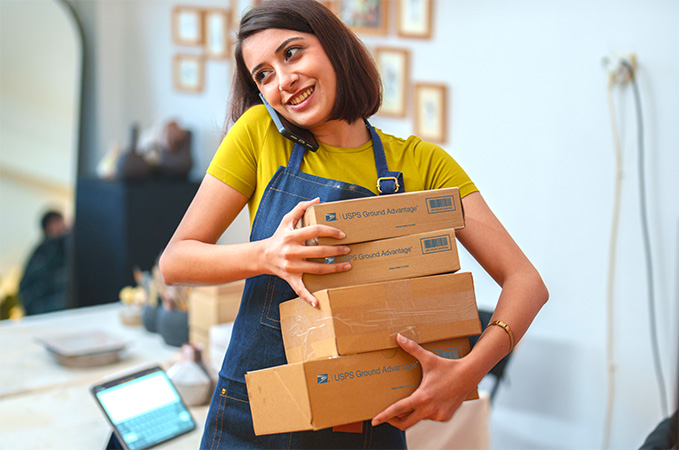 A person on the phone holding Ground Advantage packages ready to ship.