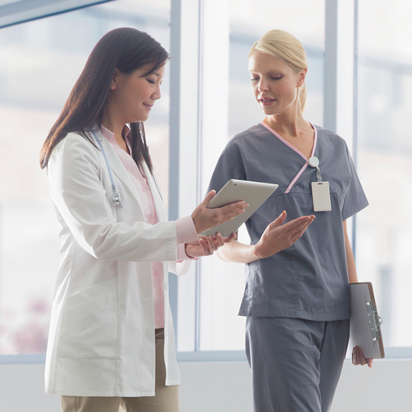 Two healthcare professionals standing and reviewing a tablet together.